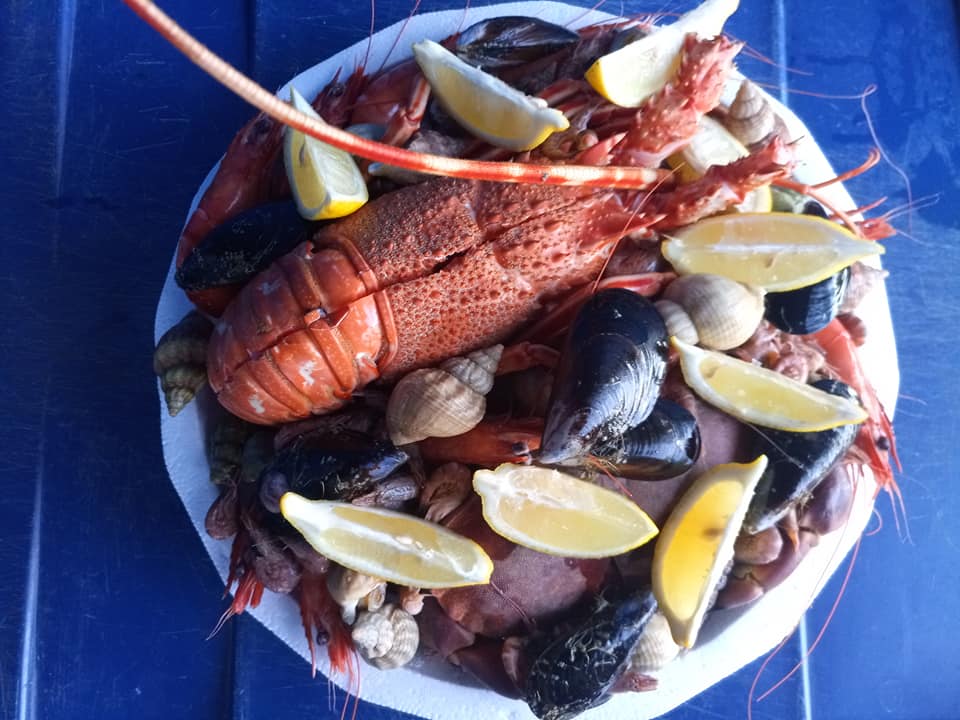 plateau de fruits de mer contenant une langouste, des bigorneaux, des moules, des crevettes, des moules